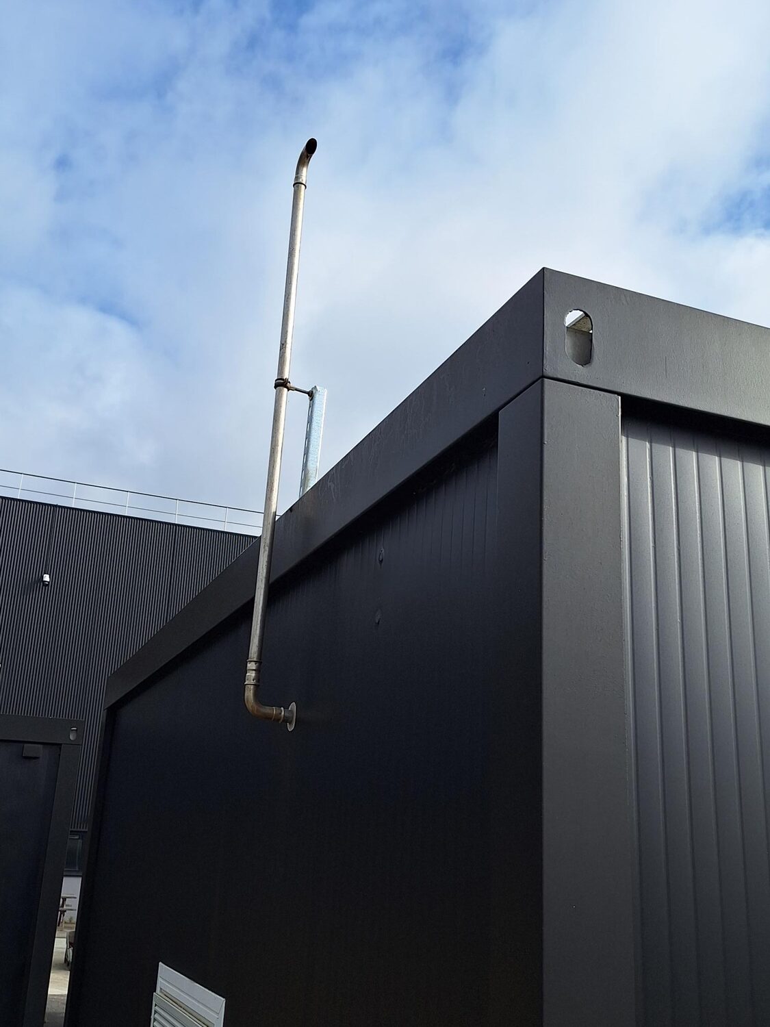 Cheminée de rejet de l'air pollué installée en façade du local, au-dessus de l'auvent